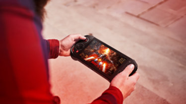 Close-up view of a man playing video games with portable console outdoors. Technology concept